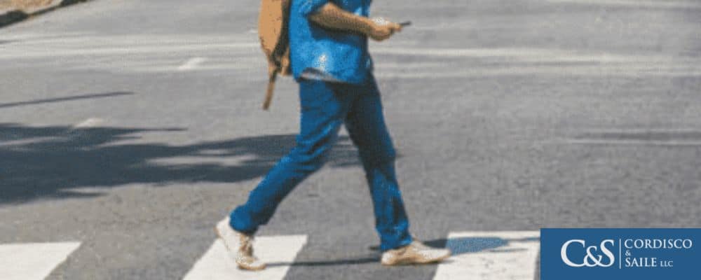 A man crossing the road while pressing his smartphone