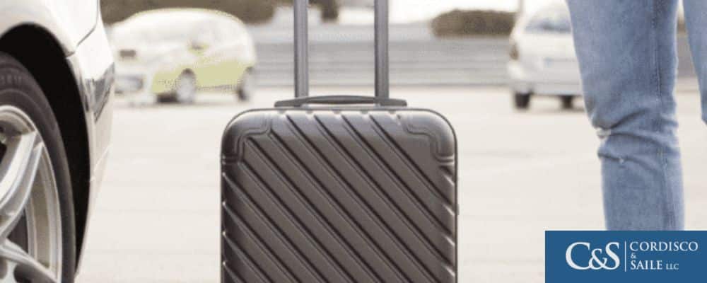 Man with luggage standing beside a rented car