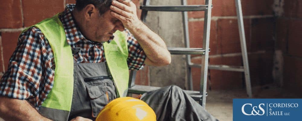 A construction worker holding his head