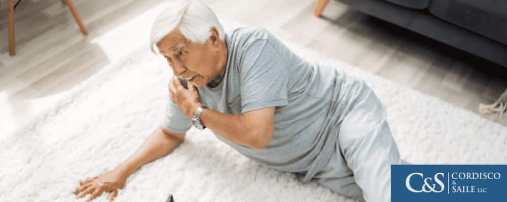 An elderly man after slipping holds his shoulder on the floor