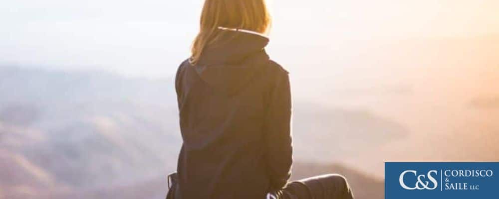 A woman sitting on a mountain reminicing