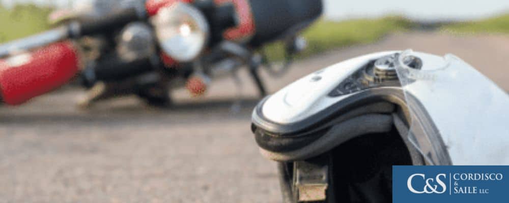 A motorcycle and helmet laying on the ground after an accident