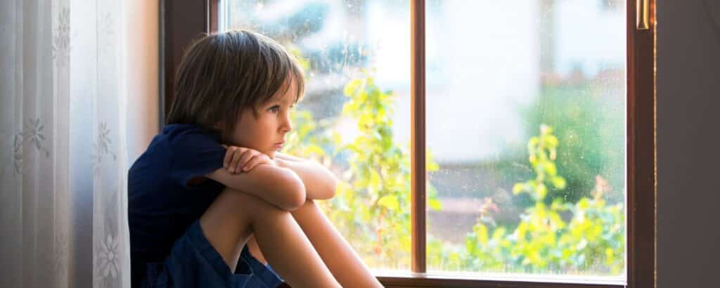 child sitting by and looking out window