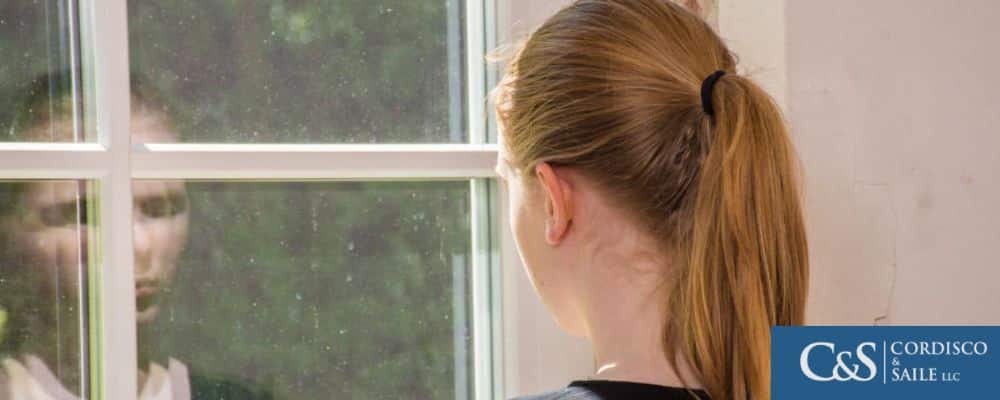 young person sadly looking outside of window