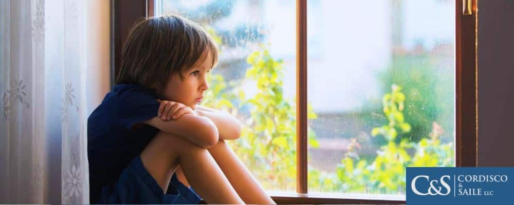 child sitting by and looking out window