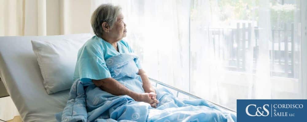 elderly person sitting in bed and looking out the window